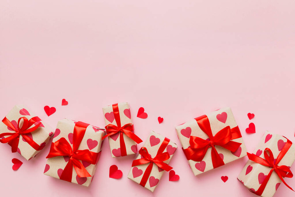 Top view photo of valentine day decorations gift box with red ribbon bow on colored background. Holiday gift boxes with top view. - Φωτογραφία, εικόνα