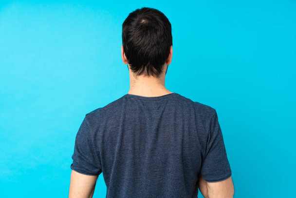 Junger Mann mit Cornetteis auf isoliertem blauen Hintergrund in Rückenlage - Foto, Bild