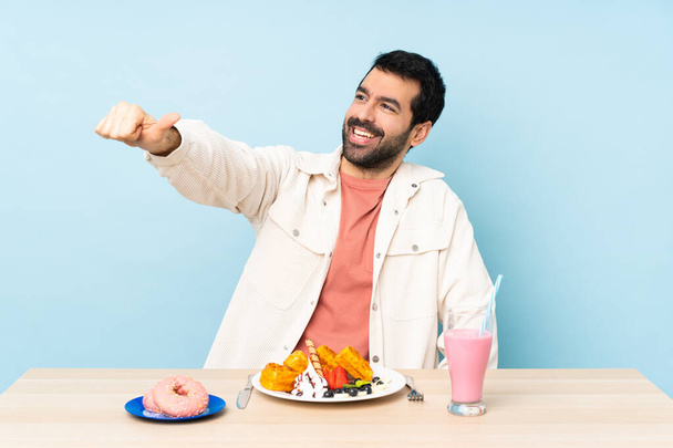 Мужчина за столом, завтракающий вафлями и молочный коктейль, показывающий большой палец вверх
 - Фото, изображение