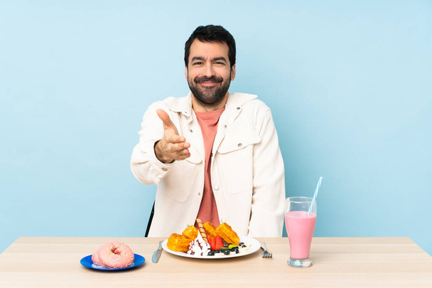 朝食のワッフルと良い取引を終了するためのミルクシェイクの握手を持っているテーブルに男 - 写真・画像