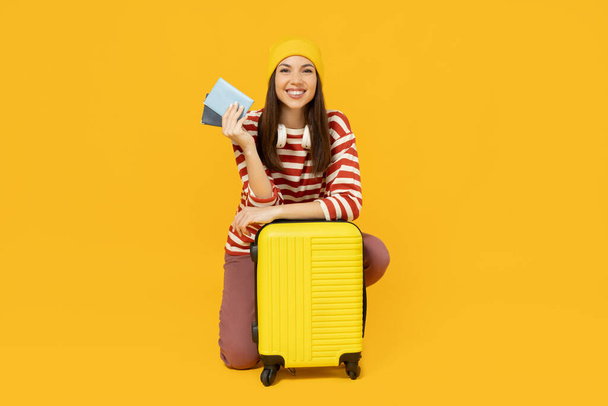 Menina com mala e passaporte em fundo amarelo, espaço para texto - Foto, Imagem