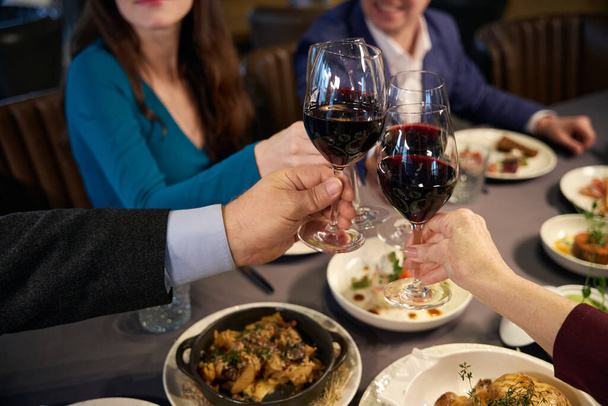 Paar zittend aan een feestelijke tafel met glazen wijn en toast - Foto, afbeelding