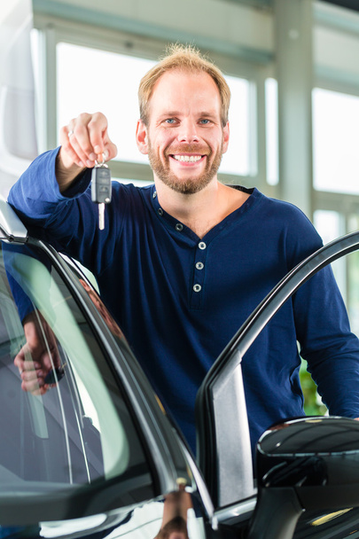 Young man with auto in car dealership - Photo, Image