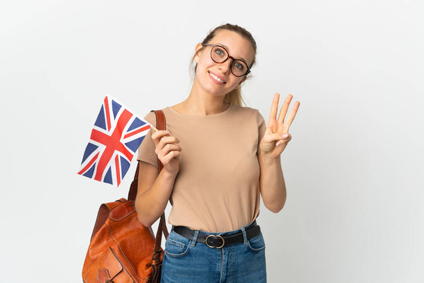 Joven rubia sosteniendo una bandera del Reino Unido aislada sobre fondo blanco feliz y contando tres con los dedos - Foto, imagen