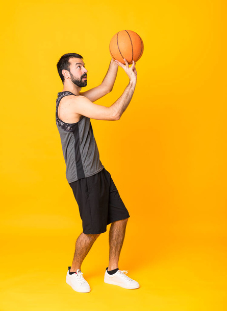 Full-length shot człowieka na odizolowanym żółtym tle gry w koszykówkę - Zdjęcie, obraz