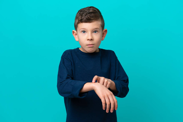 Kleiner Junge isoliert auf blauem Hintergrund macht die Geste, zu spät zu sein - Foto, Bild
