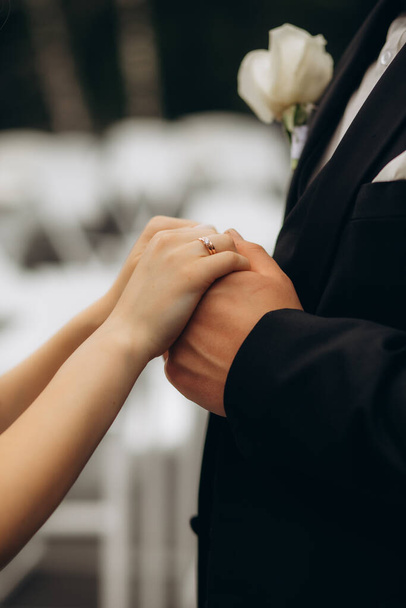 結婚指輪を持つ男女の写真.若い結婚したカップルが手を握る,式の結婚式の日. 新婚夫婦の手と結婚指輪。 . 高品質の写真 - 写真・画像