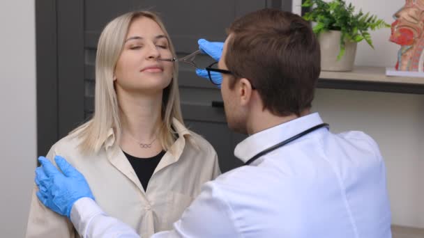 耳鼻咽喉科医は耳鼻咽喉科の診察中に若い患者の鼻を調べる - 映像、動画