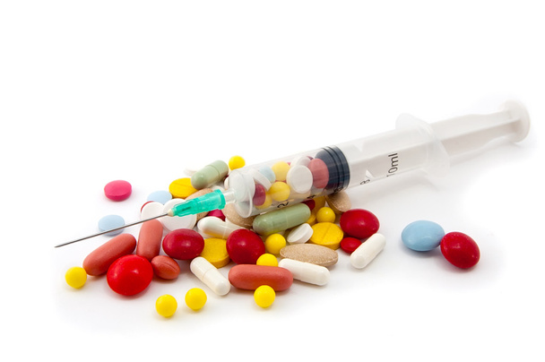 Syringe op een stapel van pillen - Foto, afbeelding