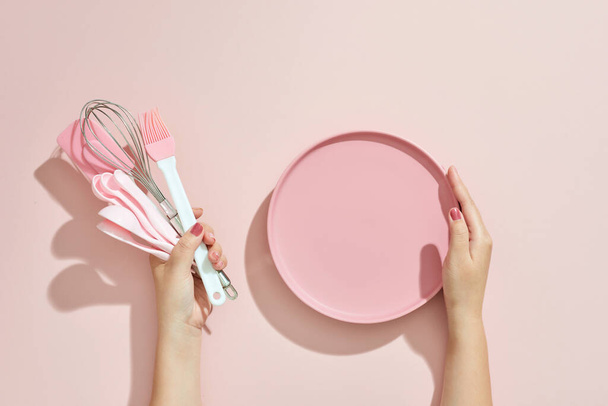 Woman hand holding kitchen utensils on pink background. Baking tools - Valokuva, kuva