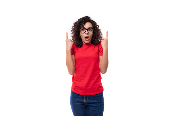 giovane donna promotrice bruna riccia emotiva vestita con una t-shirt rossa con spazio per stampare identità. - Foto, immagini