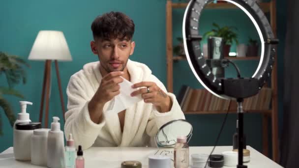 Male beauty blogger in a bathrobe running a blog about beauty and skin care records lessons in a live broadcast for social networks. Copy space - Footage, Video