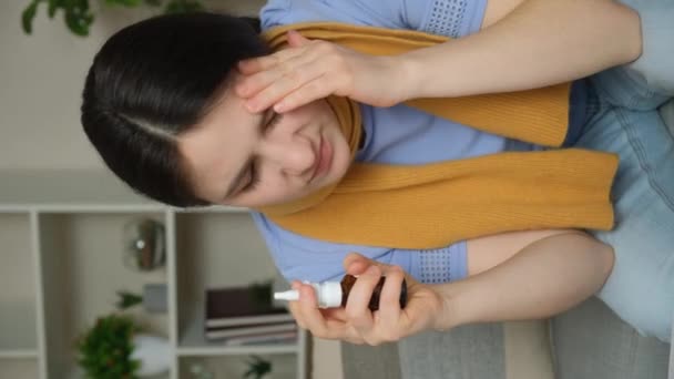 Una mujer enferma con rinitis se rocía medicina en la nariz. - Imágenes, Vídeo