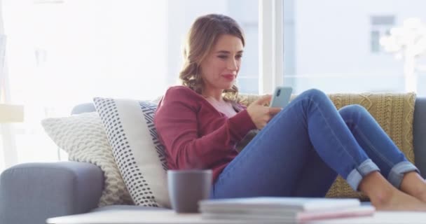 Happiness, couch and phone, woman laughing at meme on social media, text or post online in apartment. Happy smile, relax and girl on sofa browsing internet for networking or streaming funny video app. - Footage, Video