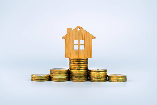 Konzepte von Finanzen, Ersparnissen und Investitionen. Immobilienkonzepte. Modell-Holzhaus und Münzen reihen sich auf blauem Hintergrund aneinander. das Konzept, Geld für ein Haus zu sparen. - Foto, Bild