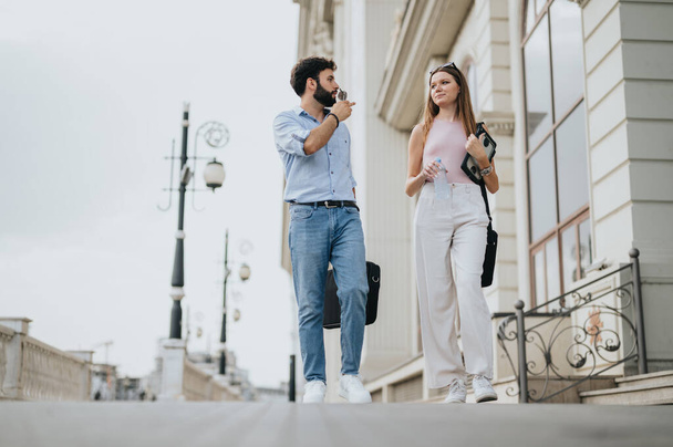 A young business couple walks in the urban city center, discussing business expansion and growth strategy, embracing new opportunities and efficient communication. - Photo, Image