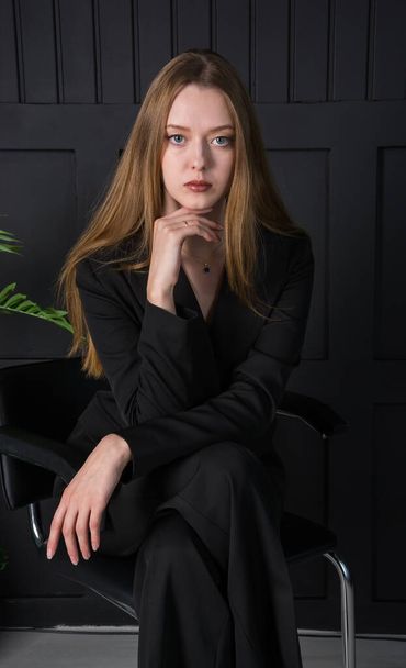 Νεαρή όμορφη γυναίκα, μοντέλο μόδας, με μαύρο κοστούμι στο στούντιο - Φωτογραφία, εικόνα
