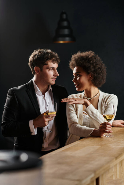 όμορφο διαφυλετικό ζευγάρι κρατώντας ποτήρια λευκό κρασί, ενώ έχουν ημερομηνία την ημέρα του Αγίου Βαλεντίνου - Φωτογραφία, εικόνα