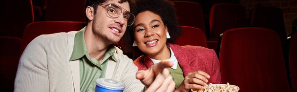 joyeux couple interracial en tenue vibrante profiter du film au cinéma sur la date, Saint Valentin, bannière - Photo, image