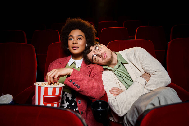 handsome man enjoying date at cinema with his african american girlfriend with head on her shoulder - Photo, Image