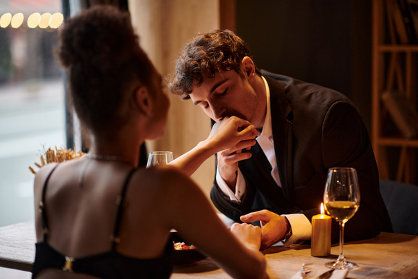 Gentleman in eleganter Kleidung küsst die Hand seiner Freundin beim Date im Restaurant, Valentinstag - Foto, Bild