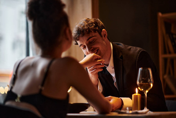 šťastný gentleman v elegantním oblečení líbání ruku přítelkyně během rande na Valentýna - Fotografie, Obrázek