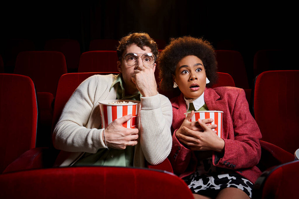 astonished shocked diverse couple in retro stylish attires watching movie at cinema, Valentines day - Photo, Image