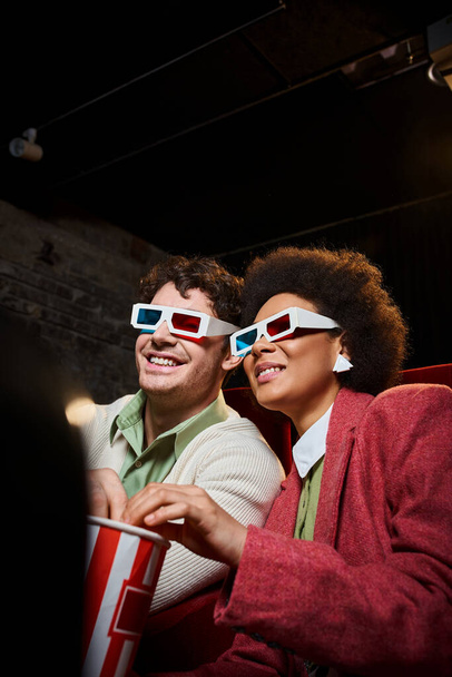 χαρούμενο πολυεθνικό ζευγάρι με ρετρό 3d γυαλιά και ποπ κορν βλέποντας ταινία στο ραντεβού στον κινηματογράφο - Φωτογραφία, εικόνα