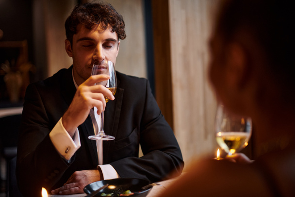 バレンタインデーの日にガールフレンドの近くで白ワインを飲むハンサムな男,ロマンチックなディナー - 写真・画像