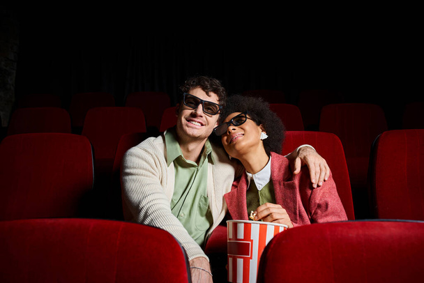 весёлая молодая мультикультурная пара в 3D-очках наслаждается своим свиданием в кино, в День Святого Валентина - Фото, изображение