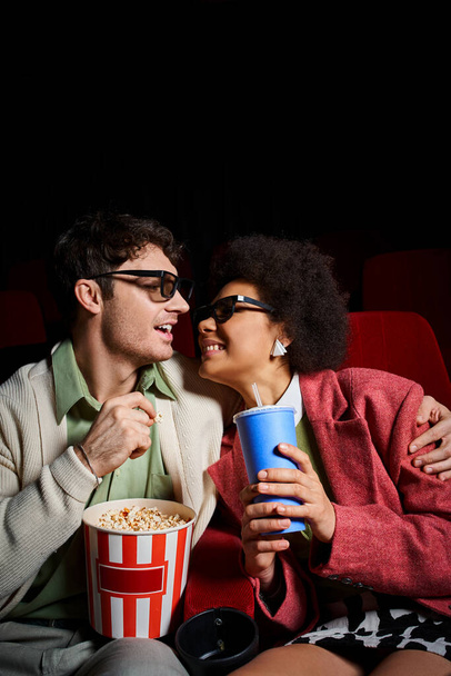 радісна мультикультурна пара в ретро вбраннях радісно посміхається один одному на побаченні в кіно - Фото, зображення