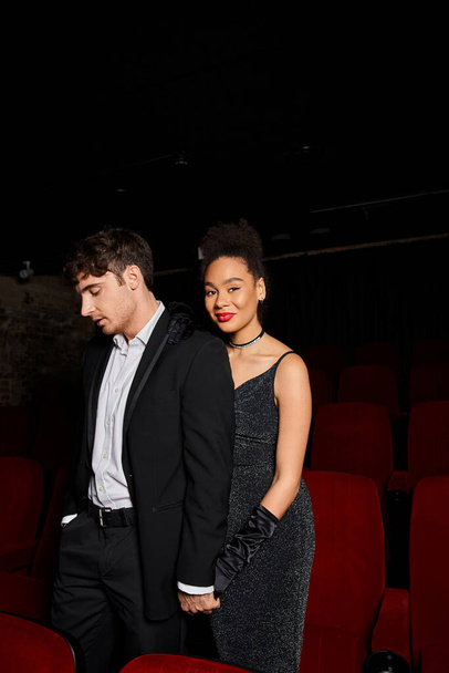 verführerisch fröhlich vielfältiges Paar in eleganten Outfits Händchen haltend im Kino, Valentinstag - Foto, Bild