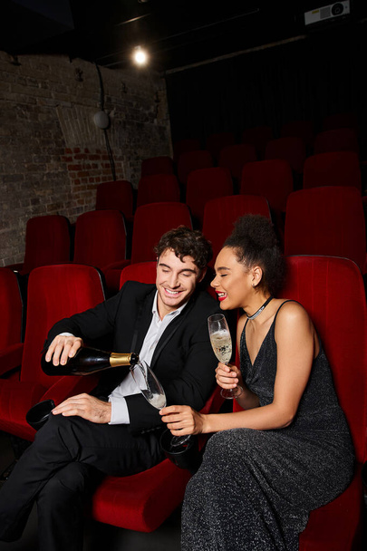 pohledný veselý muž nalévání šampaňské na jeho africké americké přítelkyně na rande na Valentýna - Fotografie, Obrázek
