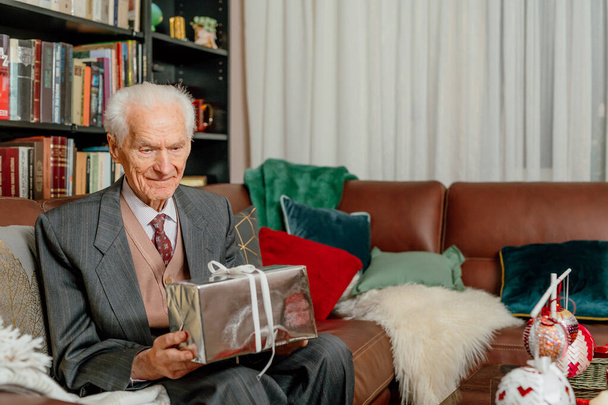 Starší muž drží vánoční dárek v ruce - Fotografie, Obrázek
