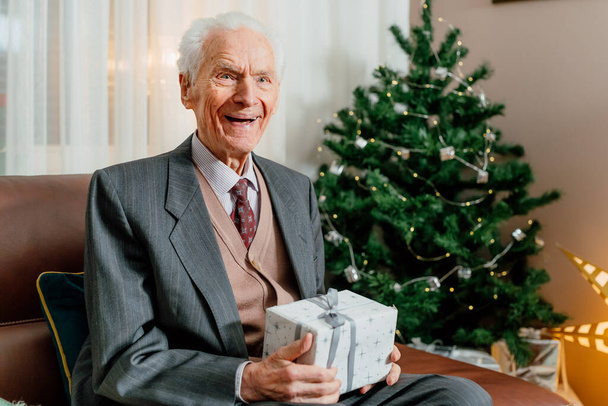 Hombre mayor sosteniendo regalo de Navidad en las manos - Foto, imagen