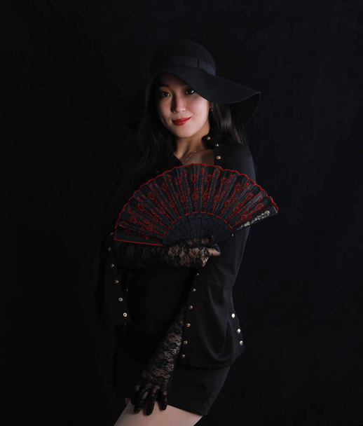 geheimnisvolle schöne Mädchen in einer schwarzen venezianischen Maske auf schwarzem Hintergrund - Foto, Bild