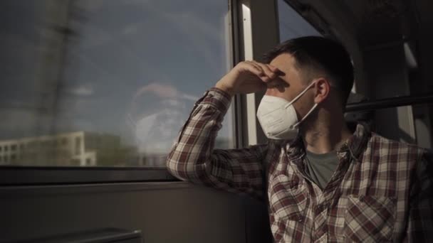 Droevige, vermoeide man met masker, zittend bij het raam op de trein in Duitsland. Personenvervoer per spoor over land. Reizen tijdens een uitbraak en pandemie. Veilig reizen met het openbaar vervoer per spoor.  - Video