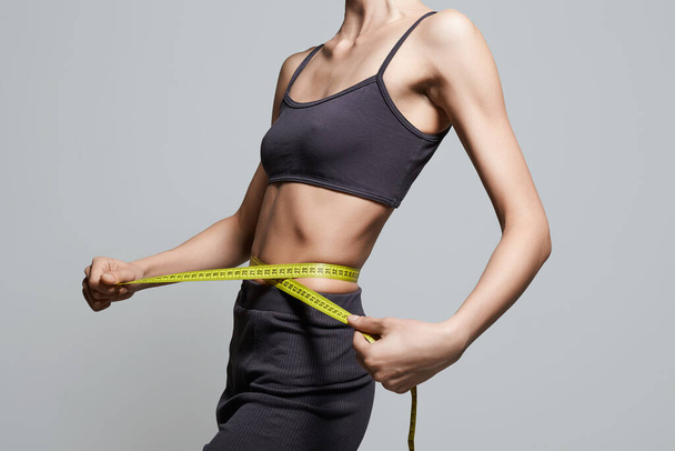 Giovane donna che misura la sua vita sottile. Slim Sport corpo Ragazza. Palestra - Foto, immagini