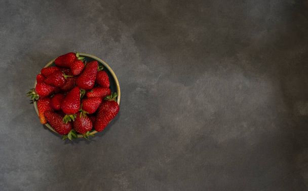 fresh red berries in circular ceramic container top view on gray background with space to fill - Photo, Image