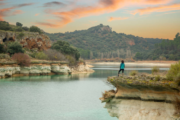 Πρόσωπο μόνο που ατενίζει τη λίμνη από ένα γκρεμό και απολαμβάνει τη φύση στις λιμνοθάλασσες της Ruidera, Ισπανία. Ταξιδεύοντας μόνος για να χαλαρώσετε. - Φωτογραφία, εικόνα