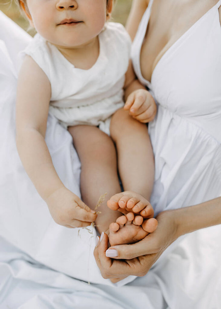 Madri mano tenendo i piedi scalzi del bambino. - Foto, immagini