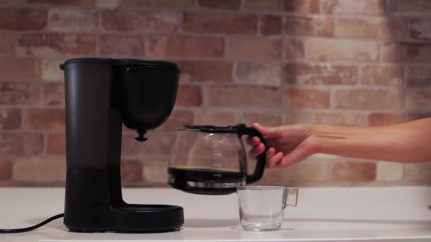 vrouwelijke handen giet koffie uit een koffiezetapparaat of koffiezetapparaat in een kopje in de keuken, vroege ochtend concept. Hoge kwaliteit 4k beeldmateriaal - Video