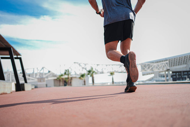 Back view of legs of unrecognizable sport man running fast, training cardio with agility. Close up portrait of male foot in a workout. Photo of a athletic guy shoes, doing a fitness speed routine - Photo, Image