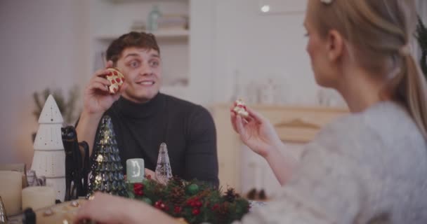 Jovem mulher e homem com decoração de Natal conversando uns com os outros em casa durante as férias - Filmagem, Vídeo