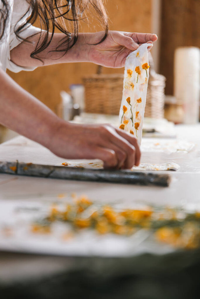 Primo piano di un artista tessile mani facendo stampa botanica su abbigliamento in fibra naturale. Coloranti artistici naturali per fiori. . Foto di alta qualità - Foto, immagini