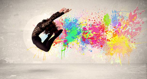 Happy teenager jumping with colorful ink splatter on urban backg - Foto, Bild