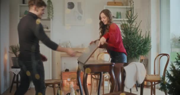 Junger Mann und Frau decken zu Weihnachten Tisch im Wohnzimmer - Filmmaterial, Video