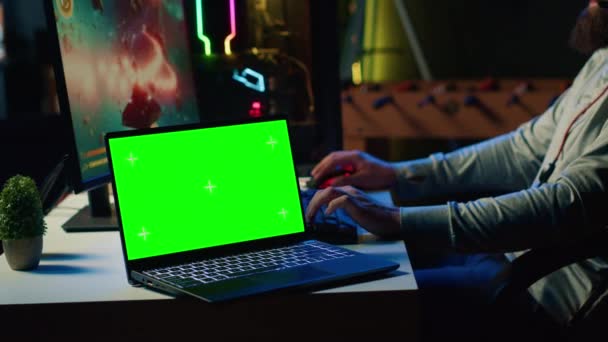 Zielony laptop ekran obok człowieka bawiącego się z przyjaciółmi online, strzelanie asteroidy razem w statek kosmiczny latający gry. Notatnik makietowy i gracz współpracujący z kolegami z drużyny w grze wideo Coop - Materiał filmowy, wideo