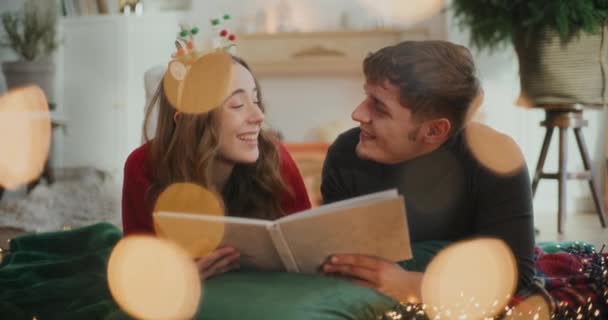 Boldog nő beszél férfi barátja, miközben nézi fotóalbum a nappaliban nyaralás közben - Felvétel, videó
