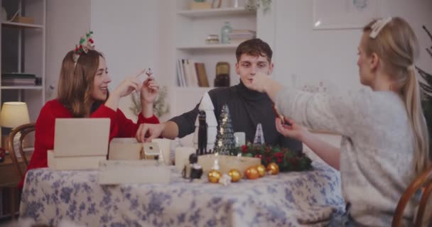 Glimlachende mannelijke en vrouwelijke vrienden met decoratie aan tafel in de woonkamer - Video